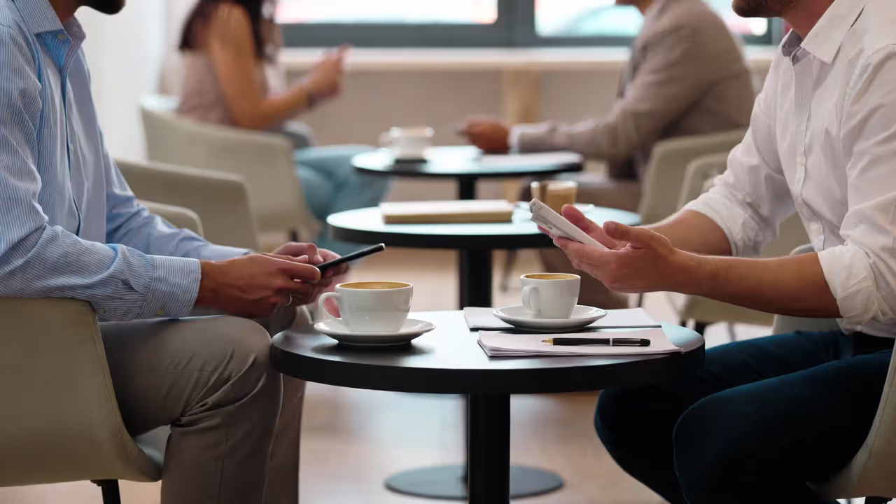 Two professionals having a one-on-one coffee meeting with a notebook on the table