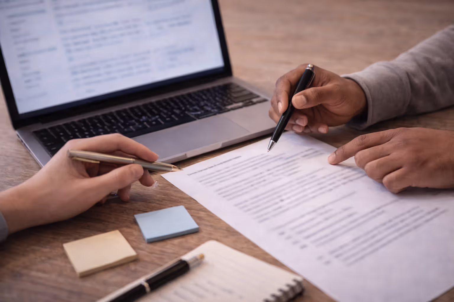 Two participants collaborating over a shared worksheet and a laptop with blurred content