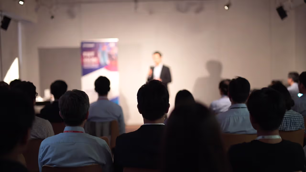 Founder pitching at an investor event with an audience in a conference room